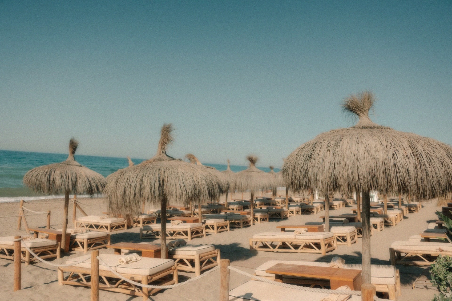 Ligbedden onder rieten parasols op een zonnig strand