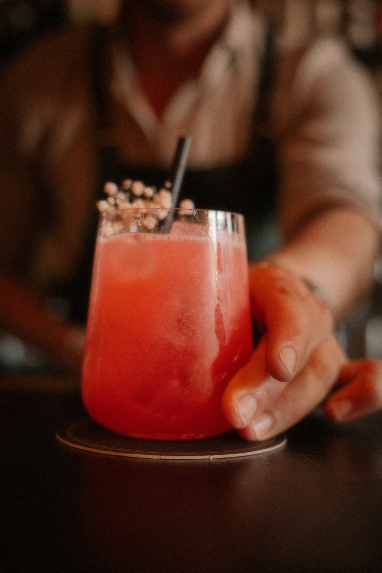 Rode cocktail met hand op een donkere bar